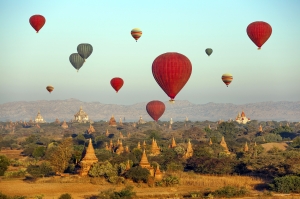 Multicolored hot air balloons over Buddhist temples at sunrise. Bagan, Myanmar.