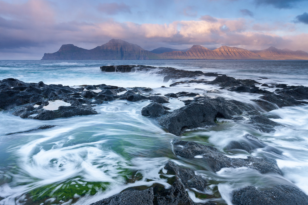 Waves crash against the rocky shores of Gjogv in the Faroe Islands, Denmark, Europe.
